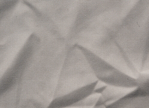Zerknitterter faltiger Stoff Textil Hintergrund mit Falten, Licht und Schatten auf Stoff