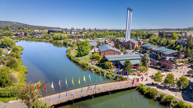 A drone view of a pedestrian footbridge over the Deschutes River in the Old Mill District in Bend, Oregon
