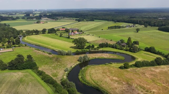 Aerial view of meandering river winding through green agricultural farmland