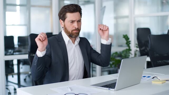 Energetic Caucasian mature business man working online dancing singing song feeling motivation fun with music radio app write in papers in office middle-aged businessman happy male dance with laptop