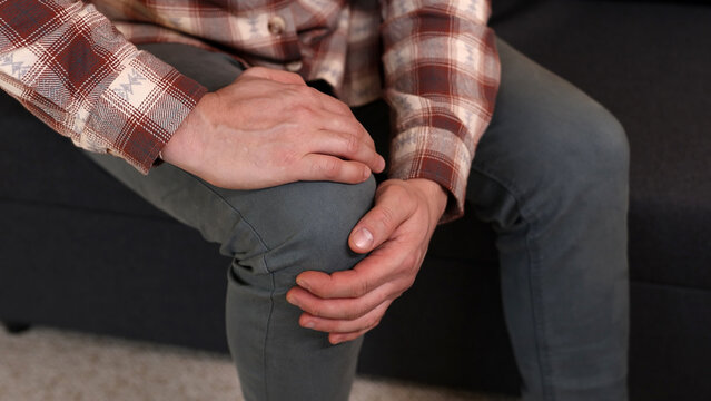 Man at home holding painful injured knee.