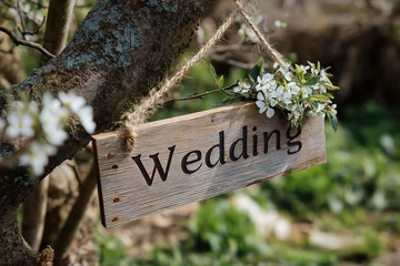 Rustic wooden wedding sign with flowers marking an outdoor ceremony location. Couples celebrate a wedding outdoors with a rustic wooden sign and floral bouquet marking the ceremony © Magryt