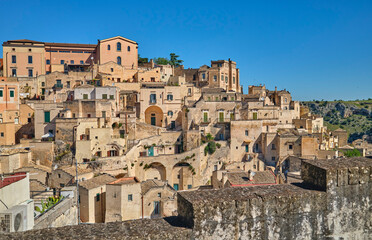 Naklejka premium street view in the medieval city of Matera, Basilicata, Italy, featuring historic stone buildings, ancient architecture, under a clear blue sky in the UNESCO World Heritage 