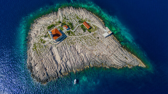 Aerial view of Blitvenica Lighthouse on a rocky islet surrounded by deep blue Adriatic sea in Zirje, Sibensko-kninska zupa, Croatia.