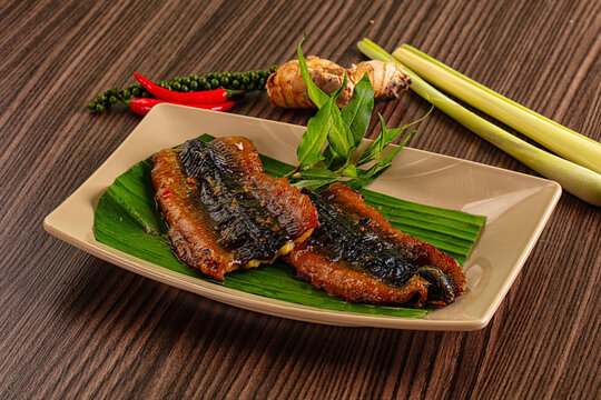 Grilled snakehead fish fillets with fresh herbs and spices on wooden table