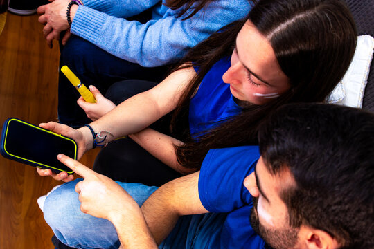 Friends watching international football tournament on smartphone at home