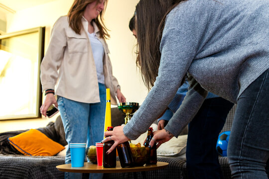 Soccer enthusiasts celebrating match victory at home with friends and drinks, enjoying a party