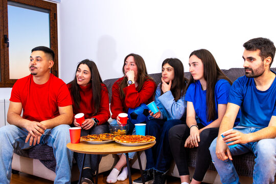 Friends watching a football tournament on tv at home, celebrating goals