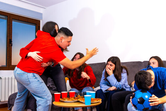 Friends reacting to football match at home, screaming, celebrating, and despairing