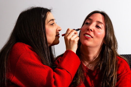 Friends painting faces for a football match, cheering for their team