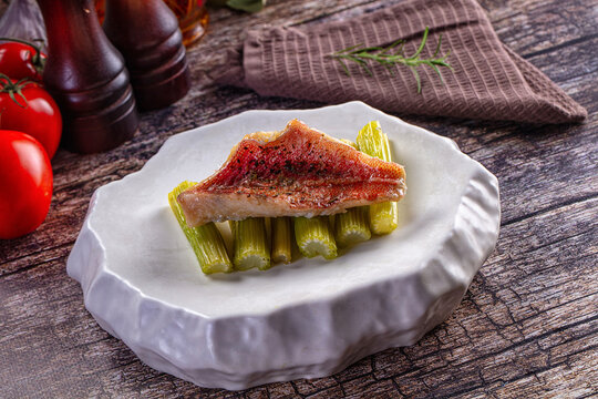 Red snapper fillet with green vegetables served on modern white plate