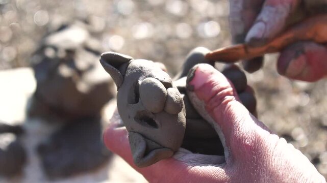 Clay crafting art, hands shaping a small figure outdoors on a sunny day