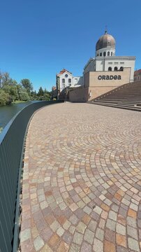 Zion Neolog Synagogue stands beside the Crișul riverside walk with the Oradea town sign visible below in Oradea, Romania. Vertical travel footage.