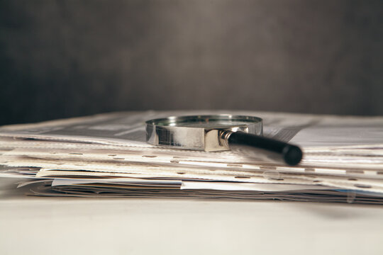 Magnifying glass on a pile of documents. Selective focus.