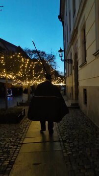 Traditional lamplighter in black cape walking down cobblestone streets at twilight to light gas lamps in Ostrow Tumski, Wroclaw, Poland, cultural lifestyle travel video clip