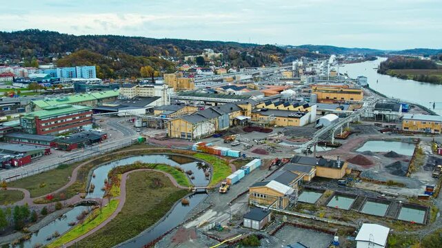 Aerial drone view of industrial area beside river featuring water treatment facility warehouses roads and landscaped retention ponds within urban environment