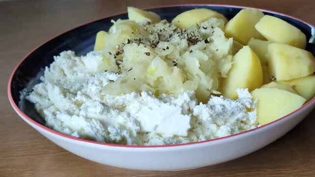 Traditional rustic meal of boiled potatoes served with fresh cottage cheese and sauteed onions in a ceramic bowl on a wooden table, healthy homemade comfort food, regional European cuisine concept