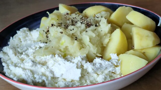 Traditional rustic meal of boiled potatoes served with fresh cottage cheese and sauteed onions in a ceramic bowl on a wooden table, healthy homemade comfort food, regional European cuisine concept