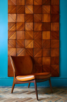 A vintage armchair nestles against geometric wood paneling, mid-century furniture fills the room with teal walls. Retro interior design elements add comfort and style to the living space.