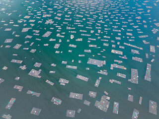 High altitude drone view showing dense patterns of floating fish farms across calm turquoise coastal waters near Song Cau. © Hanoi Photography