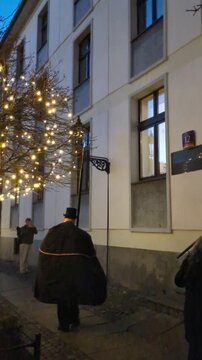 Traditional lamplighter in black cape and top hat lighting a vintage street lamp at dusk on the cobblestone streets of Ostrow Tumski, Wroclaw, Poland, cultural lifestyle travel concept