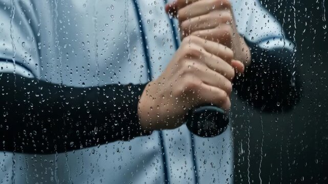 A baseball player holding a bat behind a rain covered glass windowpane