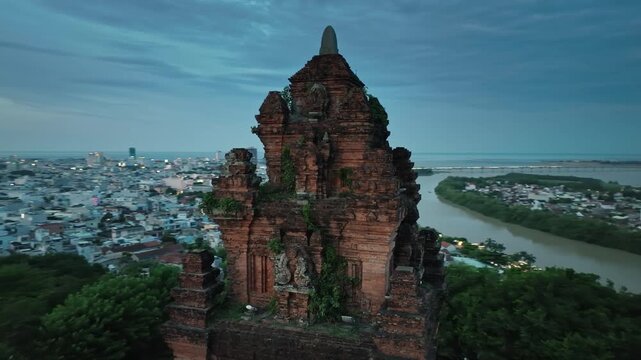 Drone close up of ancient Nhan Tower above Tuy Hoa city beside Da Rang River during blue hour, Vietnam.