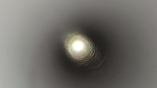Inside view of long round or spherical pipe hole with deep blurry exit end with mysterious light. Clean and smooth steel or aluminum metallic underground pipeline tube vent empty space concept.