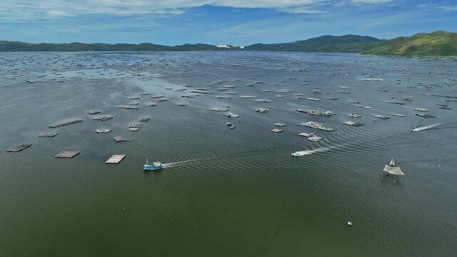 Aerial video of floating aquaculture farms and fishing boats operating across sheltered coastal waters near Song Cau, Dak Lak province, Vietnam.
