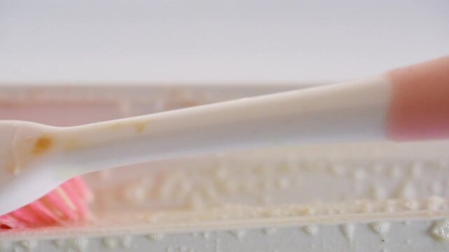 Closeup of cloth wiping and toothbrush final touches on refrigerator seal revealing clean white gasket and removed residue, satisfying reveal, tidy kitchen maintenance moment