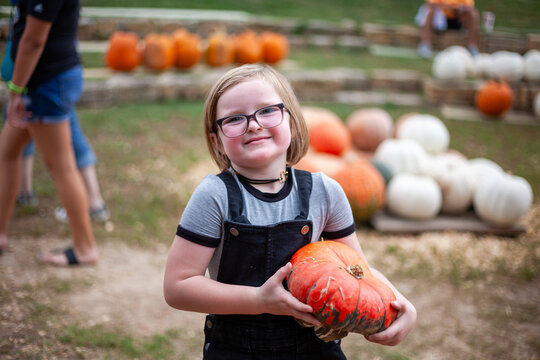 Child holding orange pumpkin outdoors.