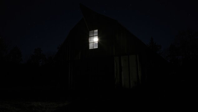 Light shining through a barn window at night