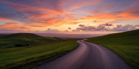 Fototapeta premium Peaceful asphalt path crossing vibrant hills under colorful sunset skies