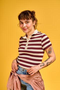 Young woman showcases summer joy in stylish attire against a vibrant yellow backdrop