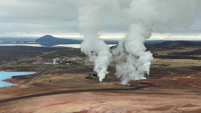 Aerial view of the Bjarnarflag geothermal power station in Iceland, showing steam vents releasing vapor into the atmosphere over a volcanic landscape