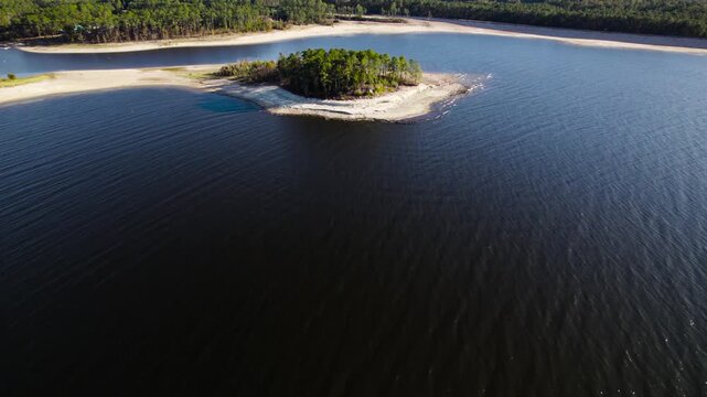 Aerial view of an island near twin dikes park on Sam Rayburn Reservoir. Small number of trees are in the center, surrounded by a sandy beach.