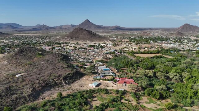 Aerial view of Lodwar, Turkana County, Kenya, with green river-side vegetation, town buildings, and rocky hills under a clear sky.