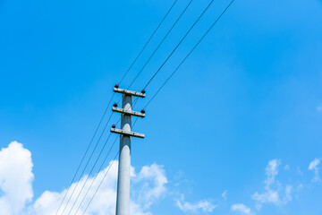 Obraz premium Utility pole transmitting electricity through power lines, providing energy infrastructure against a blue sky with white clouds