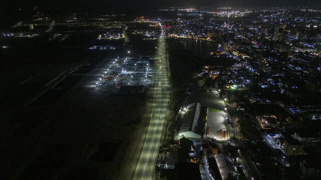 Aerial view of the illuminated Coastal Road stretching towards the city skyline at night with industrial sites and bright floodlights under a dark sky Lekki, Lagos, Nigeria.