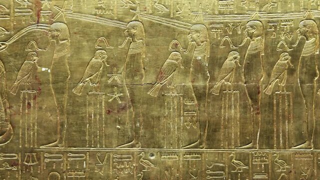 Closeup of golden Tutankhamun shrine panel with goddess and mummified figures relief.