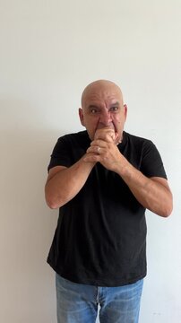 Hombre latino de 50 a&ntilde;os con gesto de rabia mordiendo pu&ntilde;o