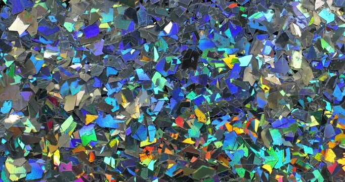 Iridescent holographic flakes slow rotation. Close-up of dense multicolored shiny fragments with vibrant blue, cyan, orange and gold reflections. 