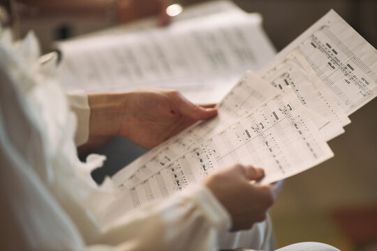 Child hands holding sheet music and studying musical notation during instrument practice, supporting music education concept. Useful for school arts programs, lessons, training