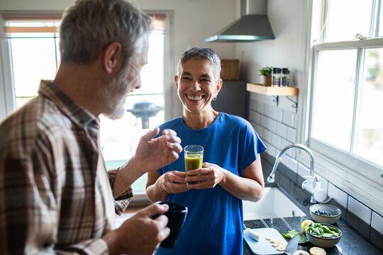 Happy senior couple enjoying healthy drinks in home kitchen