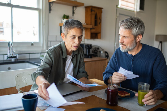 Middle-aged couple reviewing bills at kitchen table