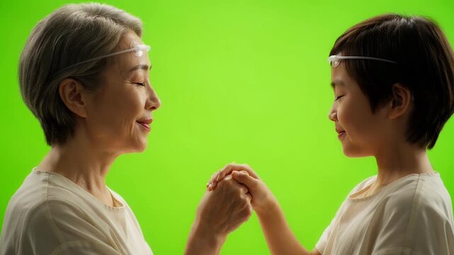 Grandmother and grandson wearing brainwave sensors holding hands on green screen.