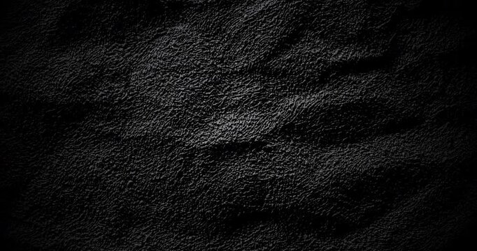 Dark Texture Abstract. Smooth rotation of dark textured surface with fine grain pattern gently moving under dramatic directional color light creating subtle highlights and deep shadows.