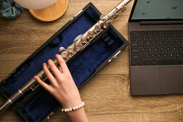 Top view of child hand practicing flute beside laptop, studying music remotely at home. Illustrating online music education, homeschooling, distance learning promotion © DragonImages