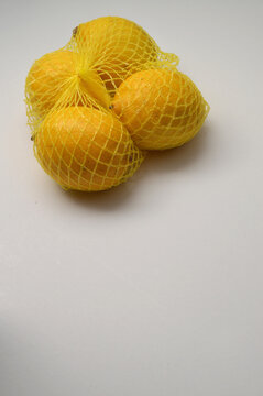 yellow lemon in a yellow mesh  on a white background corner cluster composition vertical layout, lemons close up with generous copy space,