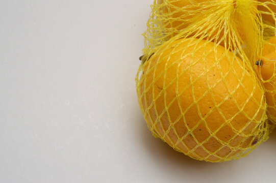 yellow lemon in a yellow mesh  on a white background corner composition horizontal layout, lemons close up with generous copy space,